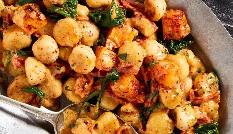 Close up of a plate of gnocchi with a spoon resting in it