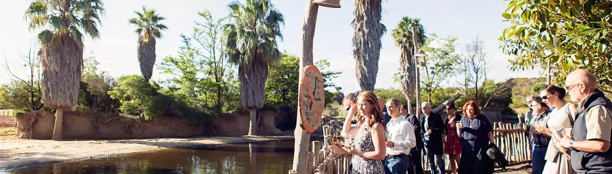 Group of people standing on a boardwalk overlooking a river.