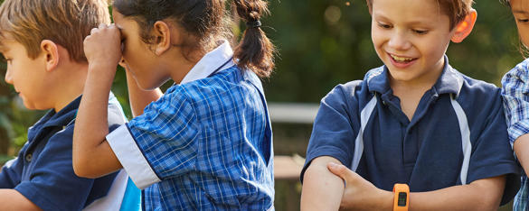 A group of young young primary school aged children sit and play dressed in blue uniforms