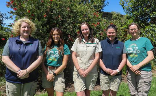 A team of zoo employees stand in a row smiling 