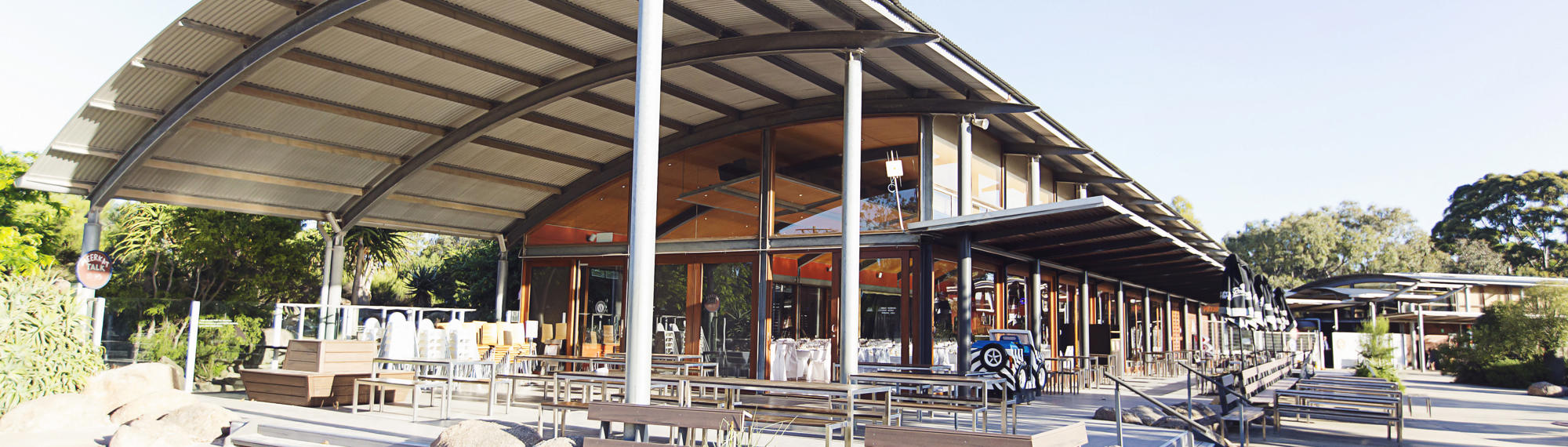 A building with a curved roof and picnic benches out the front.